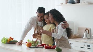 A family engages in cooking activities in a modern kitchen. They chop vegetables and enjoy each other's company, highlighting their bond and shared love for healthy eating. video