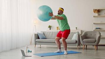 A millennial man engages in a workout at home, focused on using a stability ball to enhance his exercise routine. video