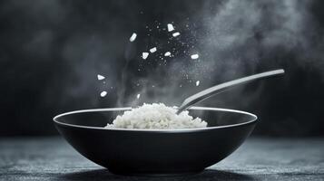 Fluffy White Rice Steaming In Dark Bowl With Spoon Resting Inside photo