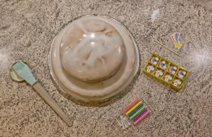 Frosted Cake with Candles and Topper on Countertop photo
