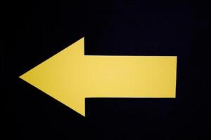 Yellow Arrow Pointing Left on Black Background photo