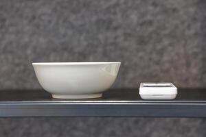 Minimalist White Bowl and Electronic Device on Shelf photo
