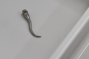 Close-up of a Metallic Hook Tool on a Smooth Surface photo