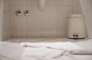Clean Bathroom Corner with Towel and Trash Can photo