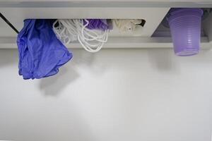 A close-up view of a storage area featuring purple and white disposable gloves, elastic bands, and a purple plastic cup. The items are neatly organized, suggesting a clean and sterile environment. photo