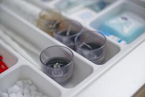 A close-up view of a drawer organizer containing various items, including three glass candle holders, sugar cubes, and small containers of toiletries. photo
