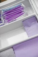 A neatly organized drawer containing purple pens and purple paper. The pens are in a plastic bag, while the paper is folded neatly, showcasing a clean and tidy workspace. photo
