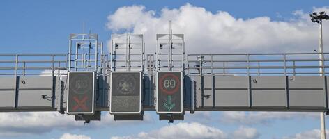 Traffic control signals displaying speed limit and lane usage instructions against a blue sky with clouds. photo