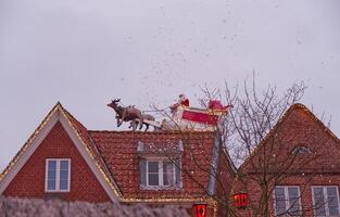 Santa Claus on Rooftop with Reindeer in Snow photo