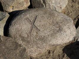 Carved X Symbol on a Weathered Rock photo