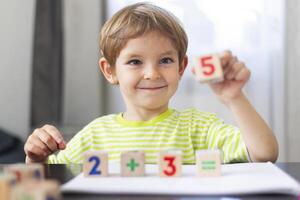 Smiling boy learning math with wooden blocks photo