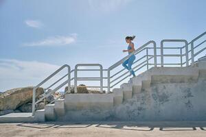 Runner jogging on staircase during workout in sunlight photo