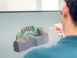 Anonymous dentist modeling jaw on computer photo
