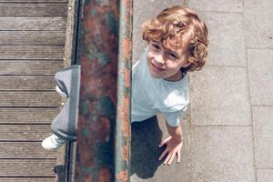 Smiling boy sitting on asphalt road photo