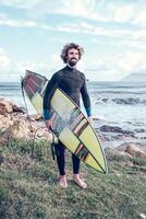Smiling Hispanic sportsman standing at seaside with surfboard photo