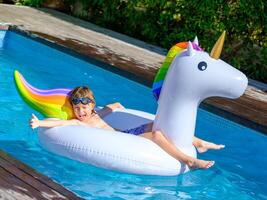 Cute kid recreating in pool lying on inflatable ring photo