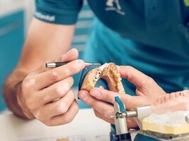 Crop dental technician man making denture on gypsum jaw casts photo