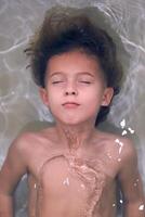 Content little kid having bath with closed eyes photo