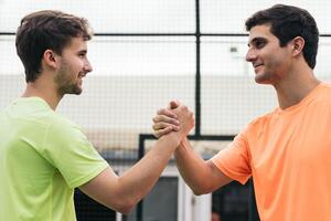 two young man paddle players shaking hands after game. fair play photo