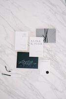 Wedding invitations with name tags lie on a white marble table photo