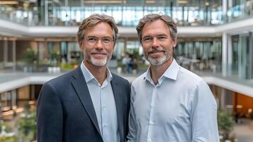 Two businessmen shaking hands with smiles after a successful deal, standing in a spacious office photo