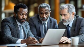 Team of diverse business professionals brainstorming ideas with a laptop open on a stylish office table photo