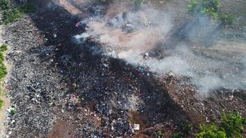Illegal dump with smoke in Bali. Pollution by plastic rubbish on burning landfill, aerial view. video