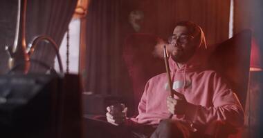Man with drink and hookah in front of TV video