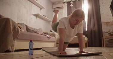 Tired young overweight lady doing buttock exercise on mat at home video