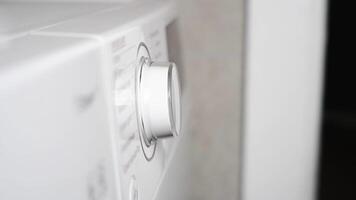 Hand turning washing machine knob to select washing cycle video