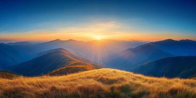 breathtaking sunrise over rolling mountains, with golden grass in foreground and vibrant sky. scene evokes tranquility and natural beauty photo