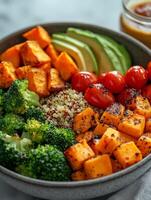 Healthy bowl with roasted sweet potatoes, quinoa, cherry tomatoes, avocado, and broccoli, showcasing vibrant colors and nutritious ingredients photo