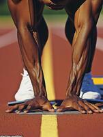 sprinter in starting position on track, showcasing strong arms and focus. athlete prepares for race, emphasizing determination and athleticism photo