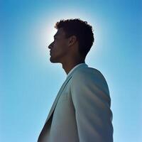 man in light suit stands against bright blue sky, creating striking silhouette. image conveys sense of calm and contemplation photo