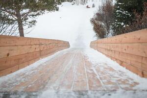 Wooden slide structure featuring snowy planks gliding down into a winter park, creating an exciting spot for children and families to enjoy sliding and playing in the snow photo