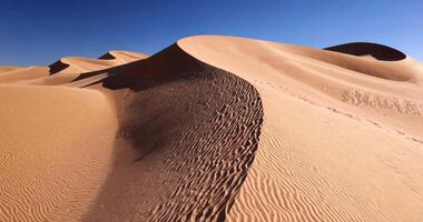 flying over a sand dune in the desert in clear weather with a clean sky video