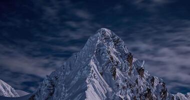 timelapse of clouds moving against the backdrop of a high snowy mountain peak in the evening video