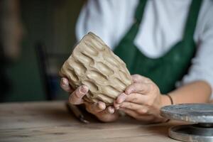 Molding craft ceramics. table in pottery studio with female artist shaping wet clay for potter bow photo