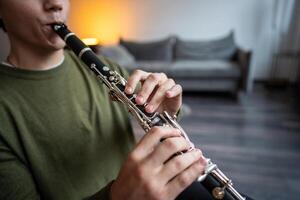 Clarinet player. Clarinetist hands playing flute woodwind music instrument at home, closeup view photo