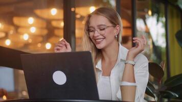 Woman delivering successful presentation via laptop in relaxed cafe setting, confident delivery impressing remote client, strong representation of business achievement and digital innovation. video