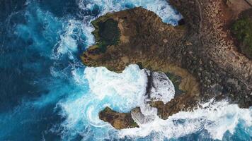 Ocean waves crashing and splashing on the rocks, drone view, top down video