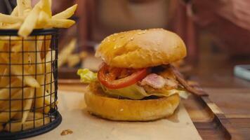 Hamburger bursting with bright toppings, expertly paired with crunchy fries for modern dining delight in bustling cafe ambiance. Hamburger showcases sizzling layers, perfect for upscale food ads. video