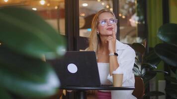 Woman handling important business call in cozy cafe, laptop open for quick data checks, phone conversation driving crucial project forward, perfect depiction of modern remote workflow. video