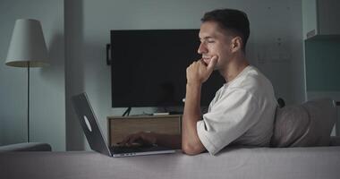 homem com computador portátil gerenciando controlo remoto tarefas, computador portátil possibilitando flexível cronograma a partir de confortável vivo espaço, computador portátil refletindo moderno carreira abordagem, ideal para freelance ou corporativo visuais. video