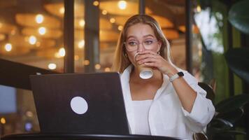 Woman coordinating with remote team via laptop in stylish cafe, interactive meeting uniting colleagues across locations, collaboration advancing shared goals, dynamic reflection of modern teamwork. video
