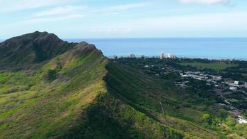 Diamond Head ridge in Hawaii with green volcanic slopes descending toward the coastline, offering scenic contrast between rugged nature and urban shoreline video