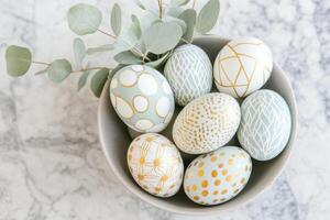 Minimalist Easter centerpiece featuring golden patterned Easter eggs with eucalyptus leaves on a marble countertop photo