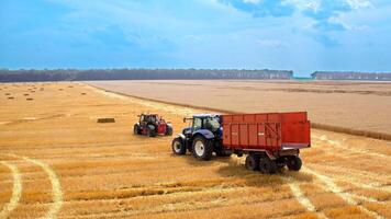 Bale machine collect straw in the field. Aerial view of country farming landscape and wheat field being harvested by combine harvester with trailer video