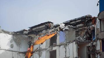 Special machine destroys a concrete house. Excavator machine with hydraulic crashers at demolition of the house. video