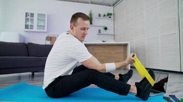 Man doing exercises at home. Man sitting on the floor at home and doing exercises with spander video